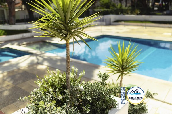 A swimming pool surrounded by potted plants and a logo for BnB Homes.