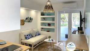 A modern living room with a sofa, a round table, and shelves with decorative items. - ID #13 BnB Homes Apartment - Studio Falesia (Albufeira)