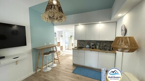 A modern kitchen with white cabinets, a wooden countertop, and a hanging light fixture. - ID #13 BnB Homes Apartment - Studio Falesia (Albufeira)
