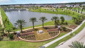 Ein Resort mit einem zentralen Teich, Palmen und einem gepflegten Rasen.