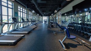 Ein Fitnessstudio mit Laufbändern, Kraftgeräten und Kurzhanteln.
