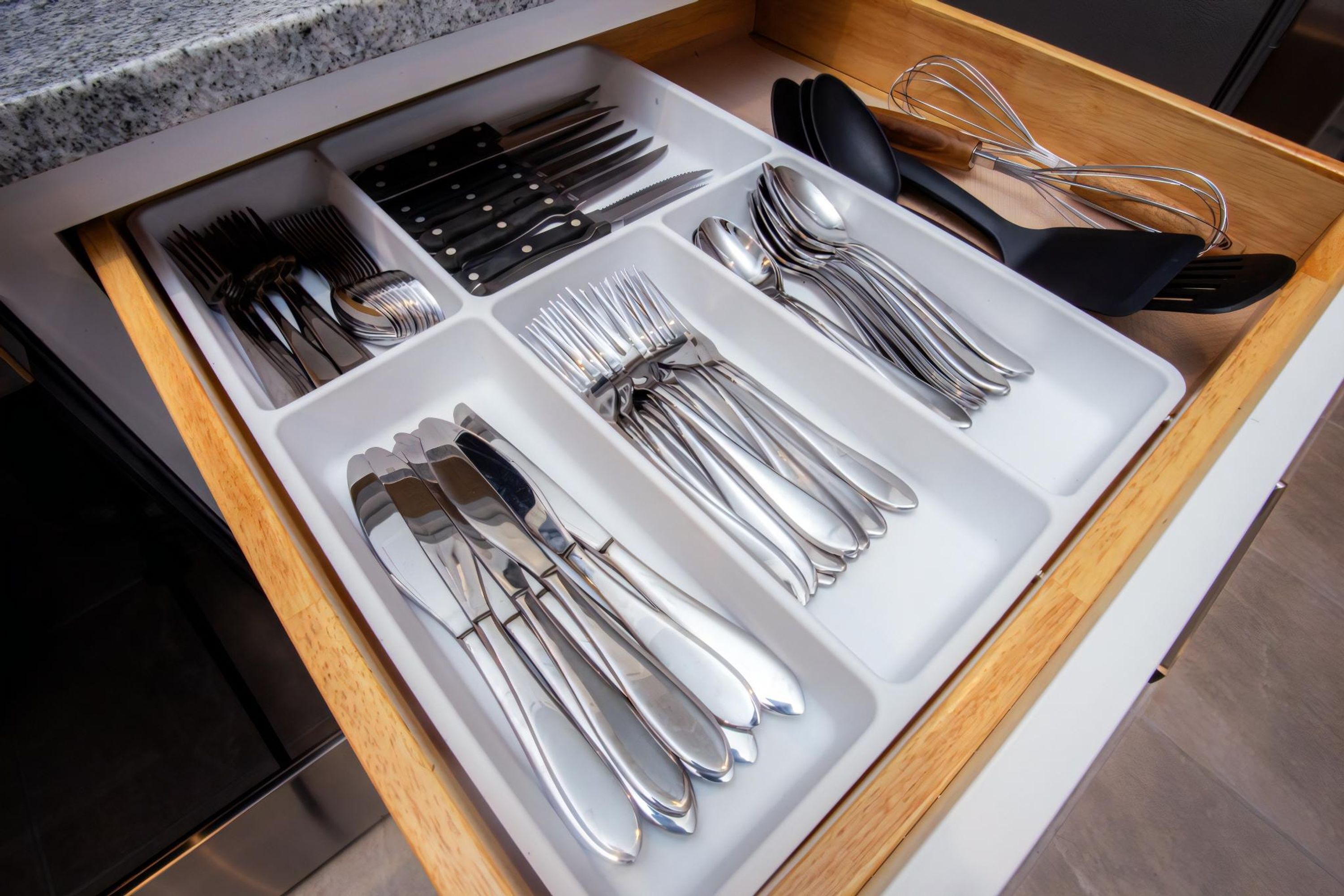 Un tiroir contenant des couverts bien rangés, notamment des fourchettes, des couteaux et des cuillères.
