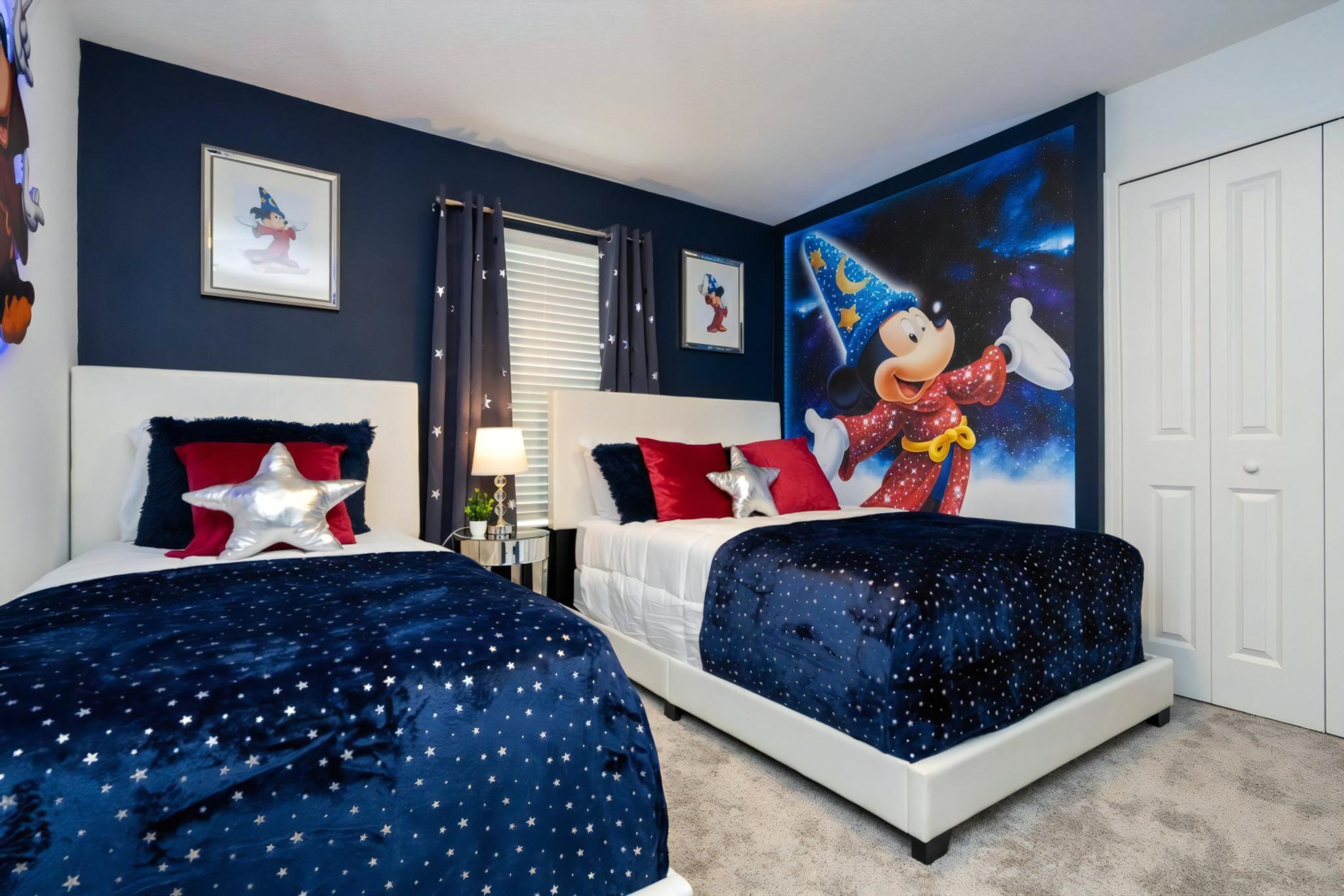 Ein Schlafzimmer mit zwei Betten, Bettwäsche mit Sternenmuster, Wandgemälde mit Mickey Mouse und Himmelszelt-Optik.