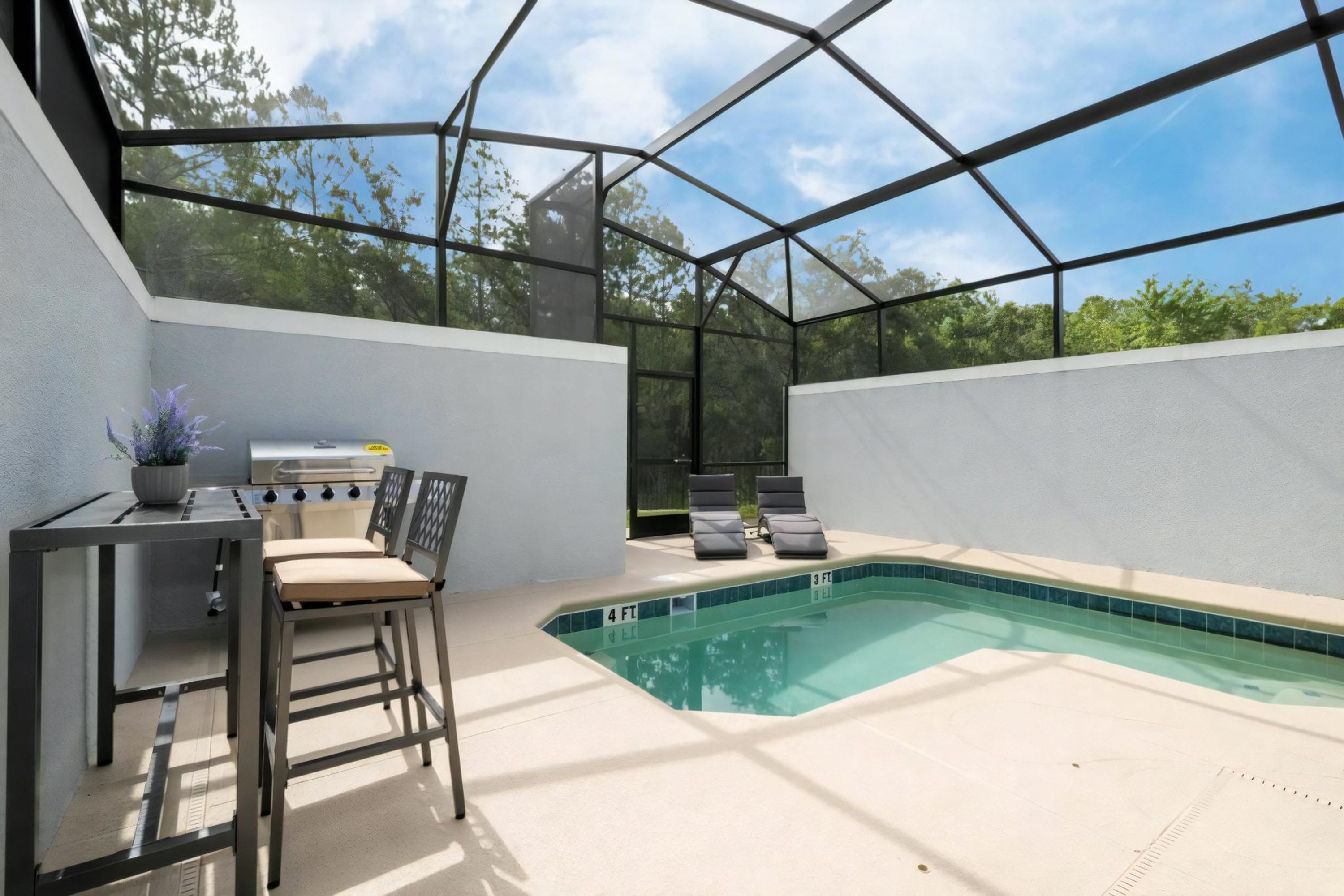 A covered outdoor area with a pool, seating, and a grill.