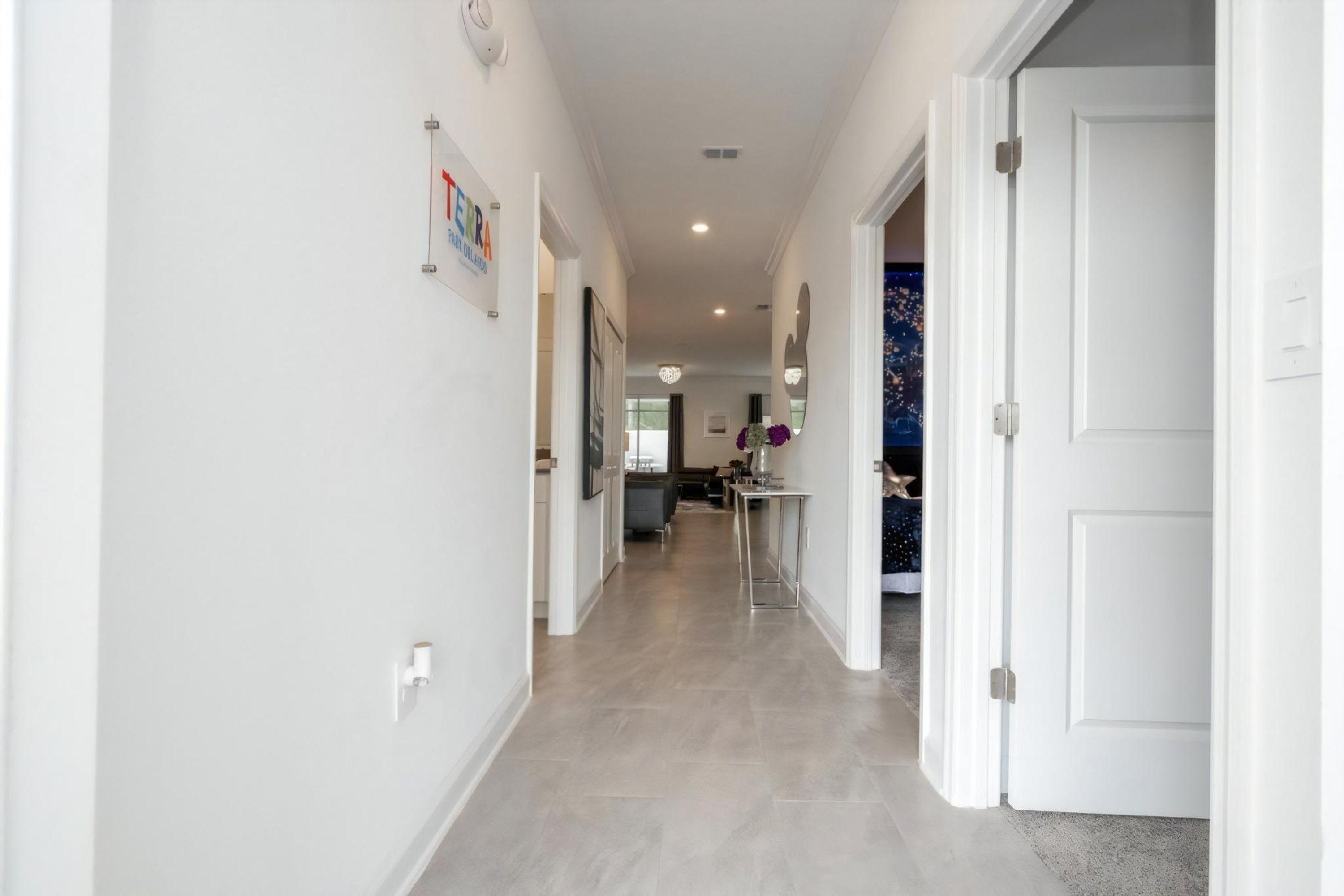 A modern hallway with a kitchen area visible in the distance, featuring a dining table and chairs.