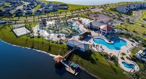 An aerial view of a resort with multiple swimming pools, a dock, and a large building with a red roof. - Storey Lake 5bed Private Pool Free Water Park (Kissimmee)