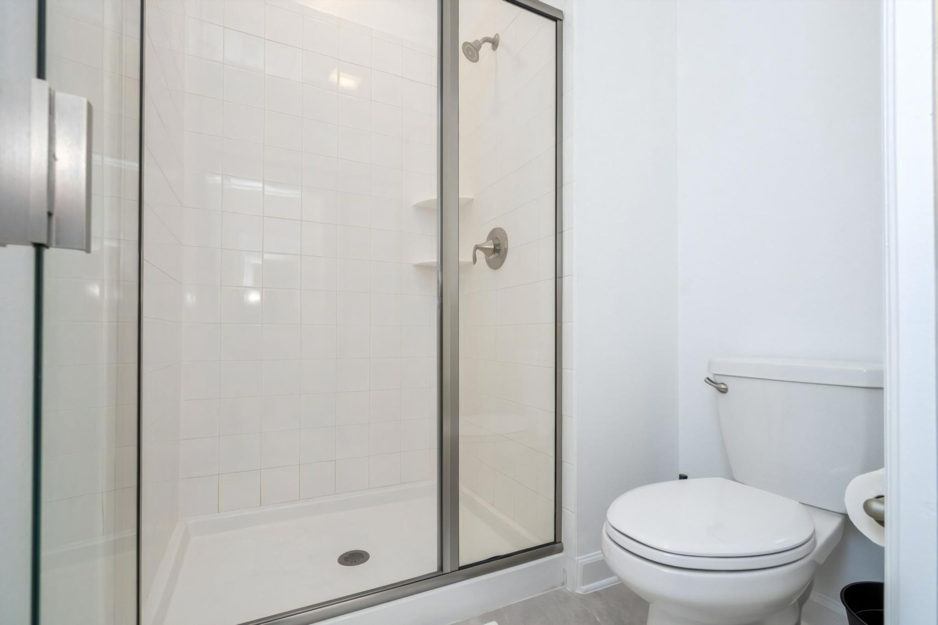 A bathroom with a glass-enclosed shower, a white toilet, and a white sink.