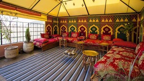 A room with a striped floor, a sofa set, a small table, and potted plants. - Riad Dar Ahl Tadla Fes (Fes)