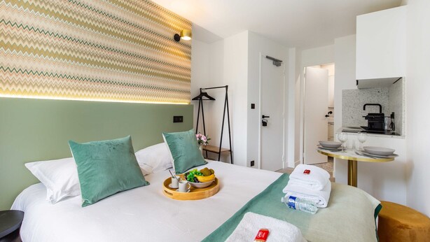 A hotel room with a bed, a breakfast tray, a towel, and a small table with a mirror and a kettle. - Bright Studio - 2P - Beaugrenelle/eiffel Tower (Paris)