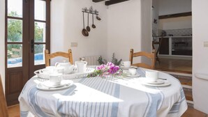 A dining area with a round table set for four, white tablecloths, and a flower centerpiece. - Villa Can Fumeral Modern and Seaview Salinas (Sant Antoni de Portmany)