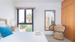 A bedroom with a bed, a mirror, a wardrobe, a chair, and a fan. - Villa Sa Marinada Modern Villa With Pool for 8 People (Sant Josep de sa Talaia)