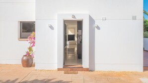 A modern building with a white facade, a visible entrance, and a potted plant with pink flowers. - Villa Sa Marinada Modern Villa With Pool for 8 People (Sant Josep de sa Talaia)