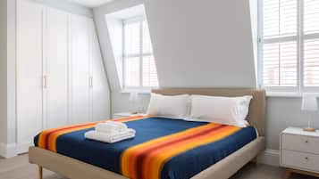 Une chambre à coucher avec un lit, une table de chevet, une fenêtre et une armoire.