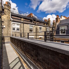 A narrow urban pathway with stone walls and a metal railing.