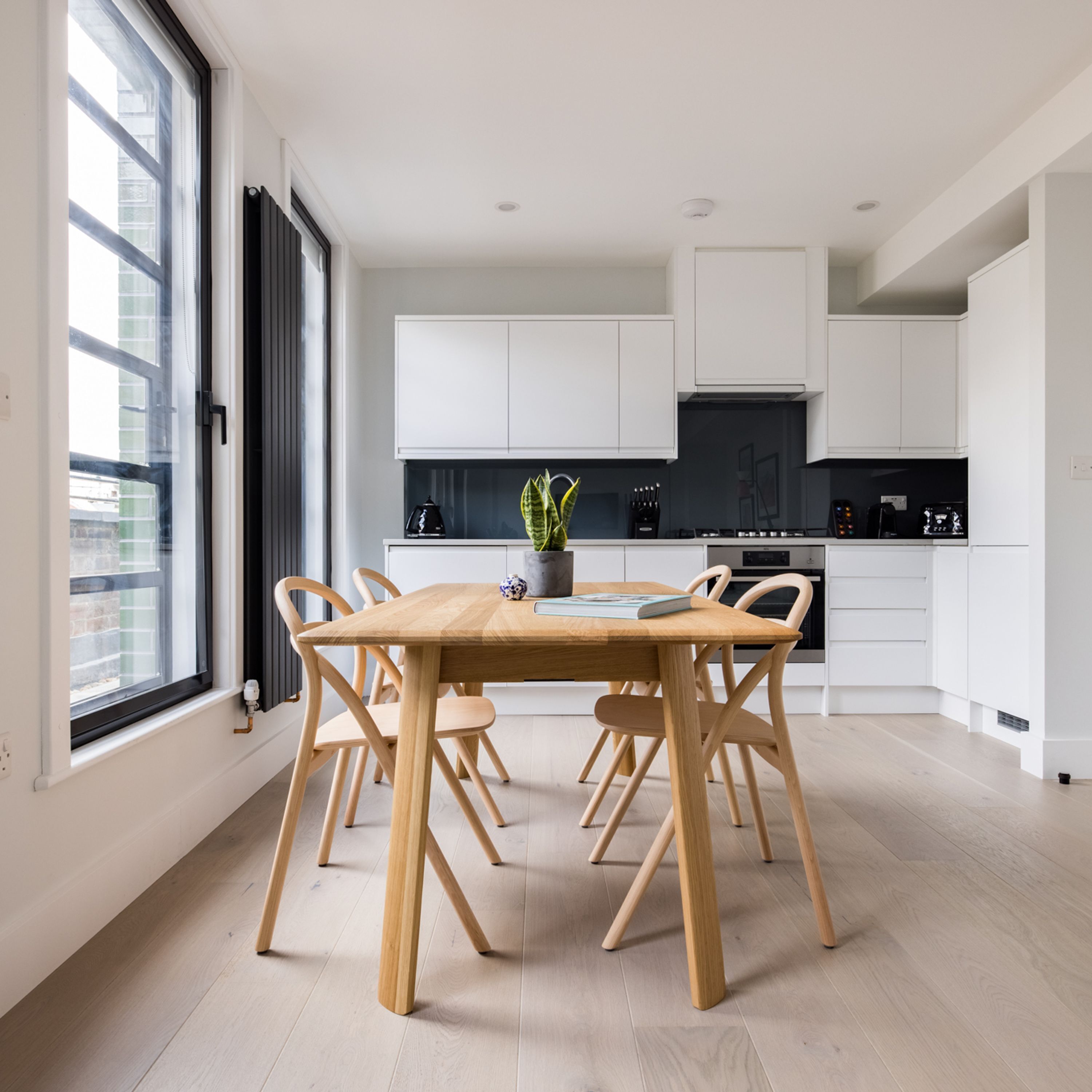 Una cucina moderna con mobili bianchi, un tavolo da pranzo in legno e sedie.