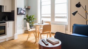 Un salon moderne comprenant un coin repas, une cuisine et une grande fenêtre laissant entrer la lumière naturelle.