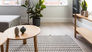 A modern living room with a large window, a floor lamp, a potted plant, a round table with two vases, and a radiator. - Calm Leicester Sq 1BR - Netflix Nespresso (London)