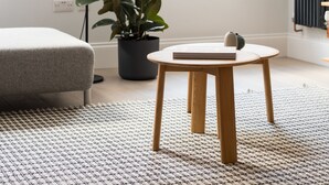 A modern living room with a grey sofa, a round wooden table with a book, a potted plant, and a floor lamp. - Calm Leicester Sq 1BR - Netflix Nespresso (London)