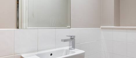 Um banheiro com pia branca, espelho acima e vaso sanitário branco.