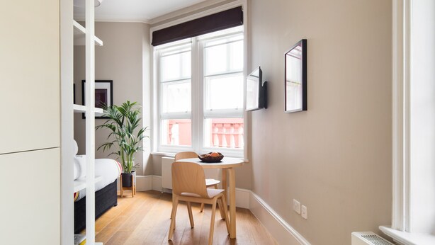A compact living space with a bed, a dining table, and a potted plant. - Funky Covent Garden Studio - Netflix Nespresso (London)