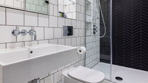 Een moderne badkamer met een wit wastafel, toilet en douche met glazen wanden.