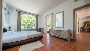 Een slaapkamer met een bed, een kapstok en een raam met gordijnen.