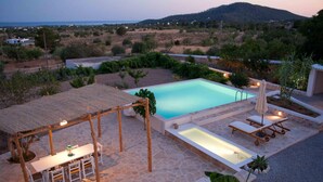 A pool area with a table and chairs, a sun lounger, and a pergola.