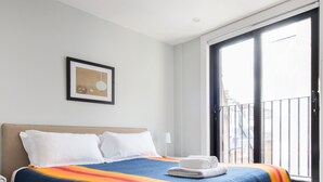 Une chambre d’hôtel moderne avec un grand lit, un tableau encadré au mur et un balcon avec vue.