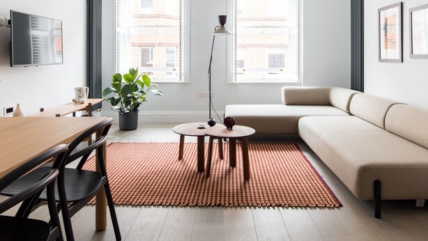 Un salon moderne avec une table à manger en bois, un canapé et une plante en pot.