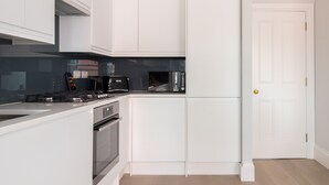 Une cuisine moderne avec des meubles blancs, un four encastré et un four à micro-ondes.