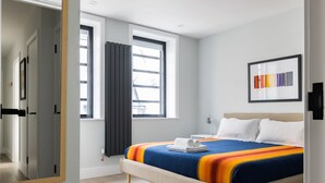 A modern bedroom with a large bed, a mirror, a window with curtains, and a framed picture on the wall. - Vibrant Leicester Square 2BR - Netflix Nespresso (London)