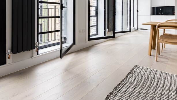 A modern kitchen with white cabinets and a wooden dining table. - Vibrant Leicester Square 2BR - Netflix Nespresso (London)
