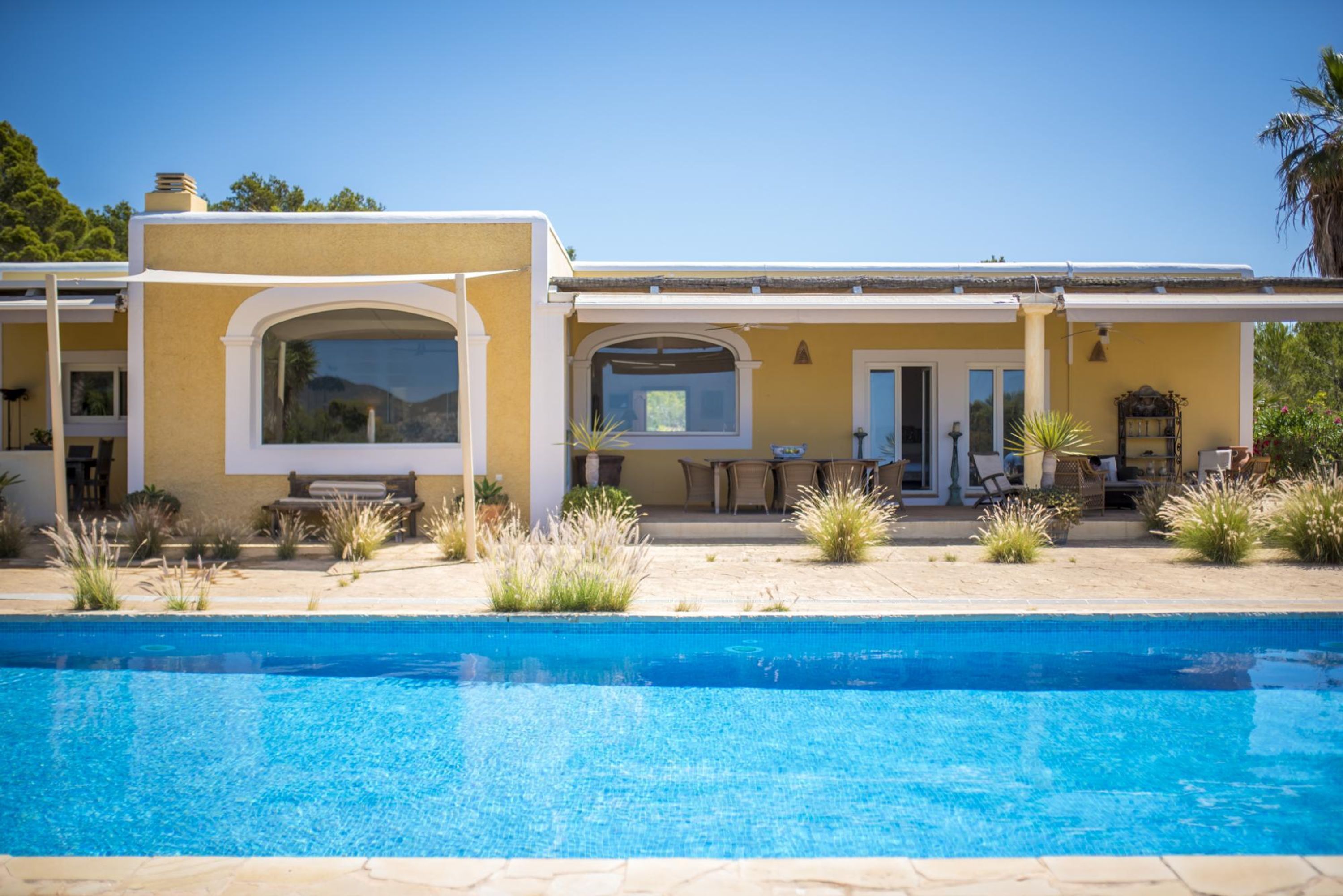 Ein modernes Haus mit Swimmingpool, Gartenmöbeln und einer Terrassenfläche.