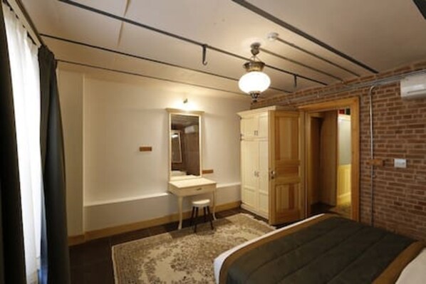 A bedroom with a bed, a desk, a chair, a mirror, and a wardrobe.