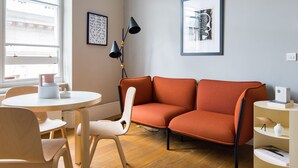A modern living room with a sofa, chairs, a table, and artwork on the walls.