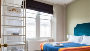 A bedroom with a bed, a wardrobe, a window, and a radiator.