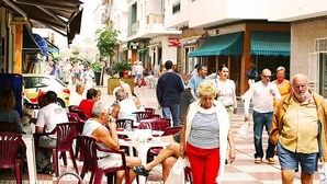 Un cafè exterior animat amb taules i cadires, envoltat d'edificis i vianants.
