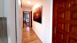 Un passadís amb terres de fusta, una porta de fusta i un quadre amb marc a la paret.