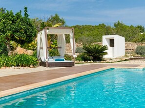 A pool area with a sunbed and a small white building. - Villa Sa Cuina Ibiza (Sant Antoni de Portmany)