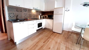 A modern kitchen with white cabinets, a microwave, and a refrigerator. - Las Galletas Ocean Plata - 2D (Arona)