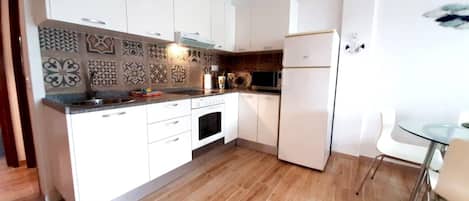 A modern kitchen with white cabinets, a microwave, and a refrigerator.