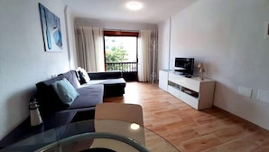A modern living room with a sofa, TV, and a glass table. - Las Galletas Ocean Plata - 2D (Arona)