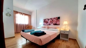 A neatly arranged bedroom with a bed, pillows, a bedside table, and a wall-mounted lamp. - Las Galletas Ocean Plata - 2D (Arona)