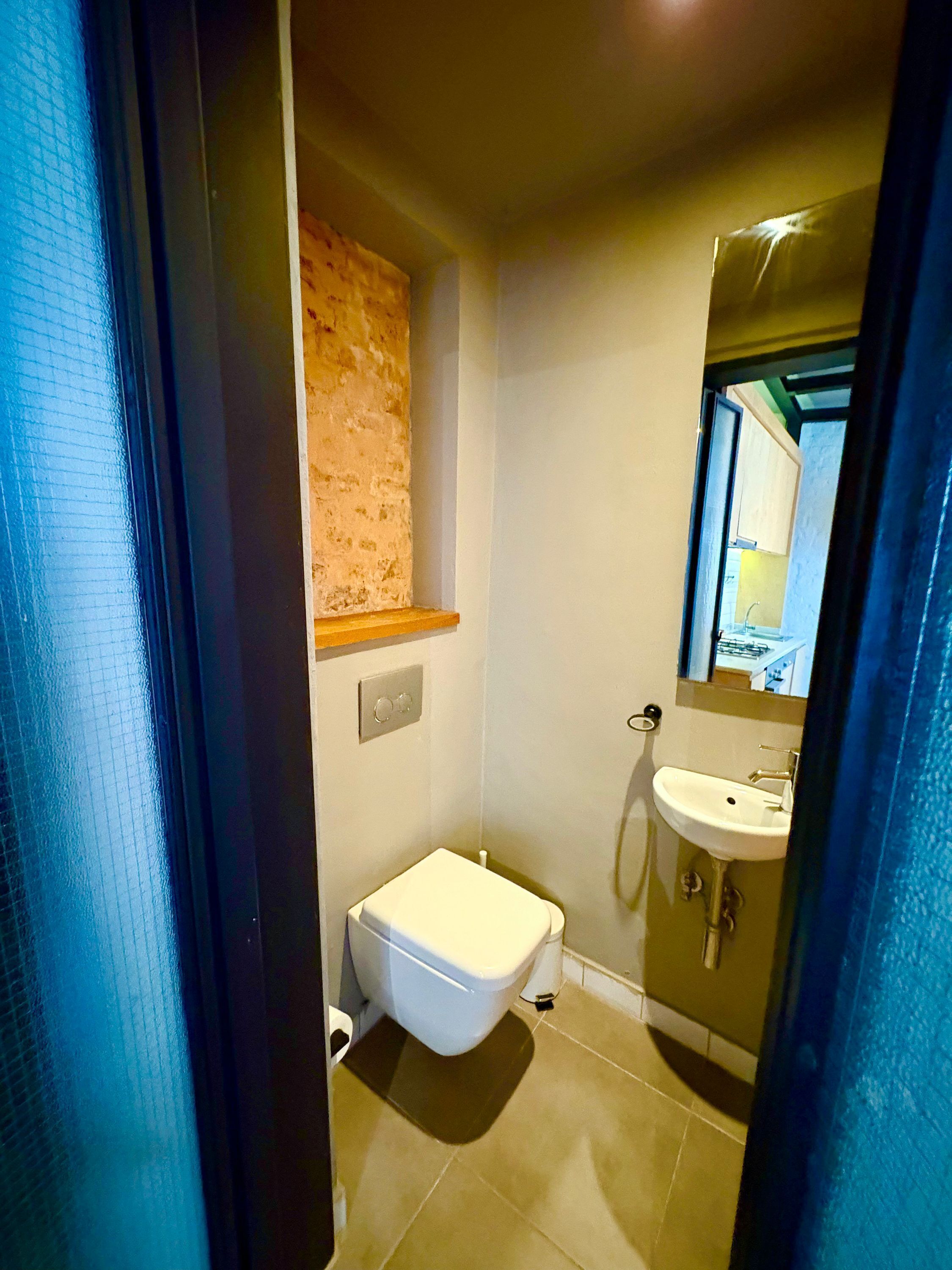 A compact bathroom with a toilet, sink, and a small window.