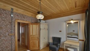 A room with a wooden ceiling, brick wall, a bed, a desk with a mirror, a chair, and a small rug. - 401 Old City Brand New Spacious With Balcony (Istanbul)
