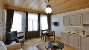 A modern living room with a sofa, dining table, and kitchen area with cabinets and a TV. - 401 Old City Brand New Spacious With Balcony (Istanbul)