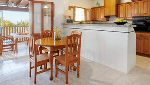 A kitchen with wooden cabinets, a central island, and a dining area with wooden chairs. - Casa Para Familias en Ibiza (Sant Josep de sa Talaia)