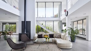 A spacious living area with a large sectional sofa, a glass coffee table, and a modern fireplace. A staircase with a glass railing leads to an upper level. - Garriguella Emporda Costa Brava (Garriguella)