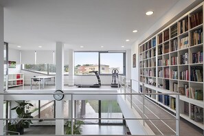 A spacious reading area with a large bookshelf, a treadmill, and a desk with a chair. - Garriguella Emporda Costa Brava (Garriguella)