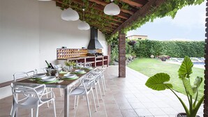 An outdoor dining area with a long table, white chairs, hanging paper lanterns, and a brick chimney. - Garriguella Emporda Costa Brava (Garriguella)